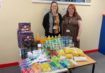 Photo of 2 staff members with a table of food donations.